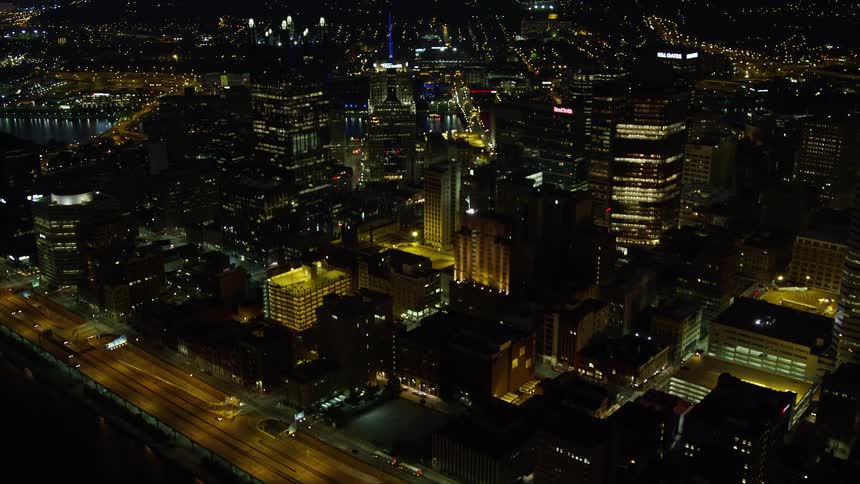 An aerial view of a city center with tall buildings at night and many lights from the buildings on