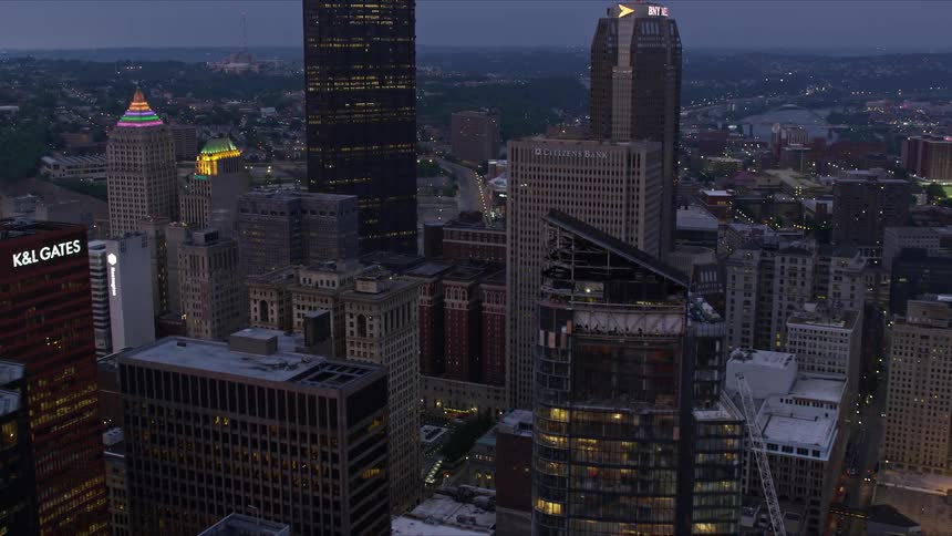 A city center with huge commercial buildings with lights on and it is getting dark