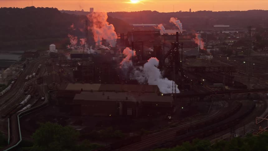 Smoke rising from the stacks of a steel plant as the sun is starting to rise