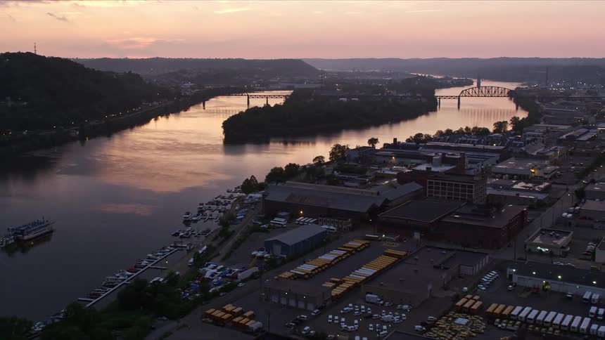 Aerial panorama of a river canal on the edge of a city and factories on a morning with a purple sky