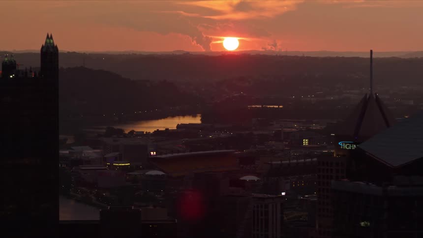 Aerial panorama of a metropolis with skyscrapers by the sea and the red sun on the horizon