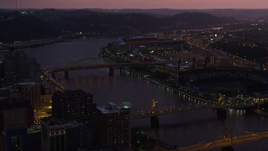 An aerial view of a city at night with a bridge running over water