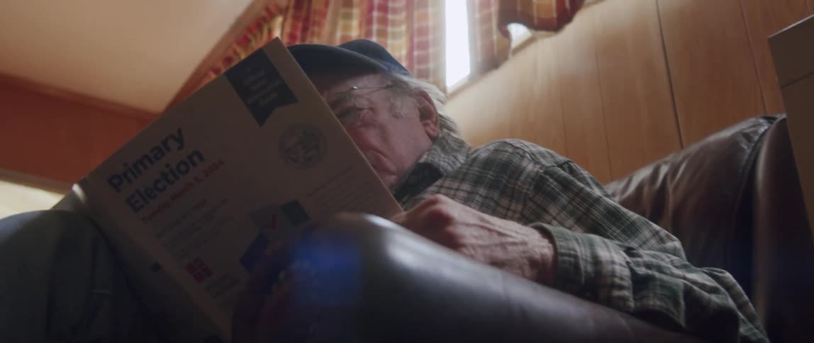 Elderly man sitting and carefully reading a newspaper