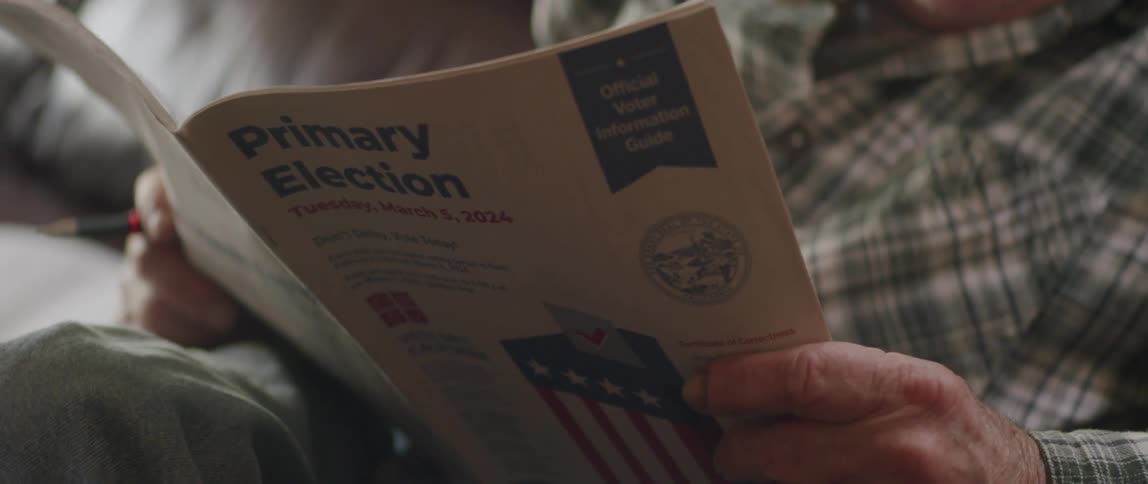 Close up of primary election booklet held by an elderly man