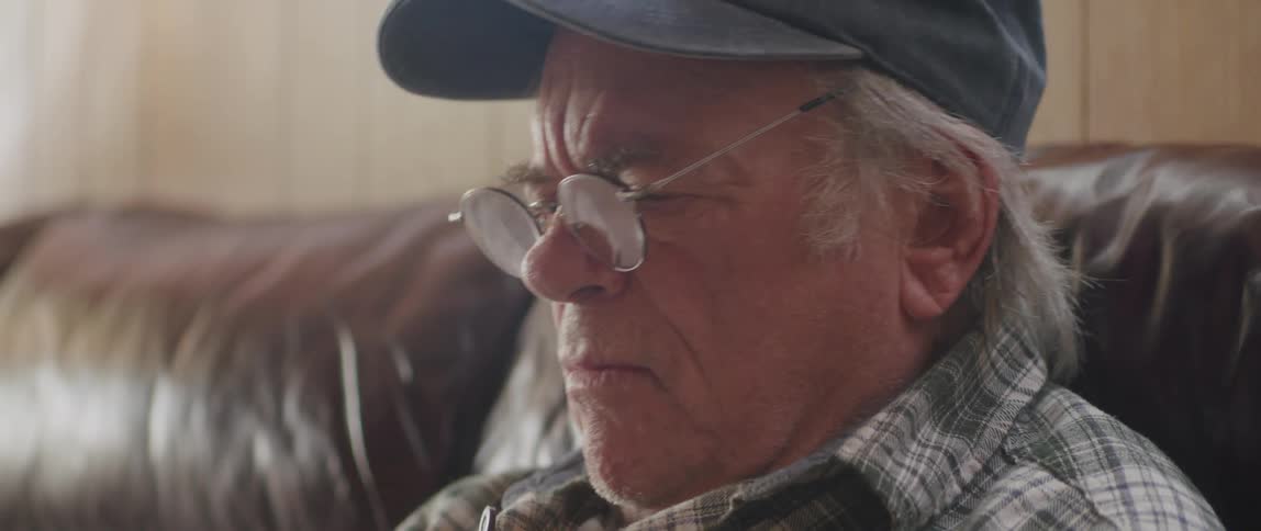 Close up of an elderly man reading in the couch at home