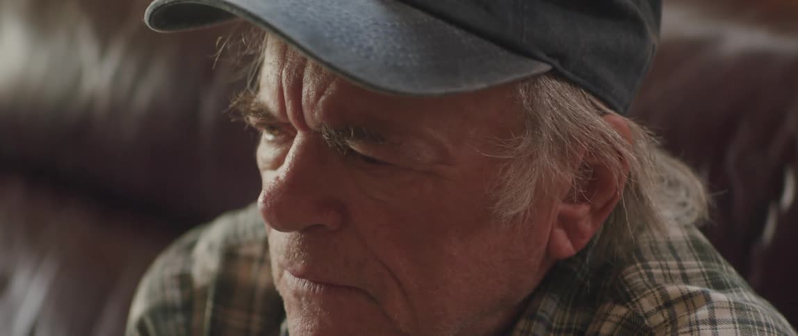 An elderly man takes off his glasses while he ponders something