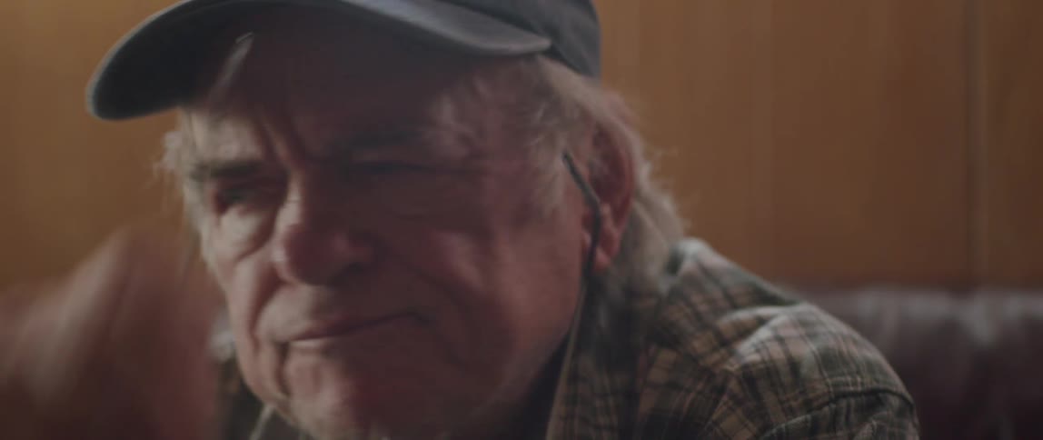 An elderly man is reading something and then takes off his reading glasses and looks around