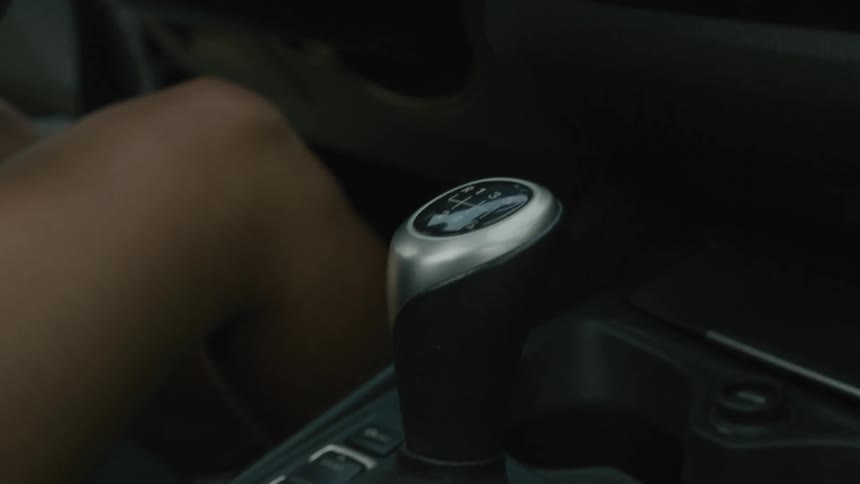 A woman shifts a car into gear