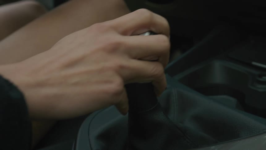 Closeup of a mans hand changing gears in a manual car
