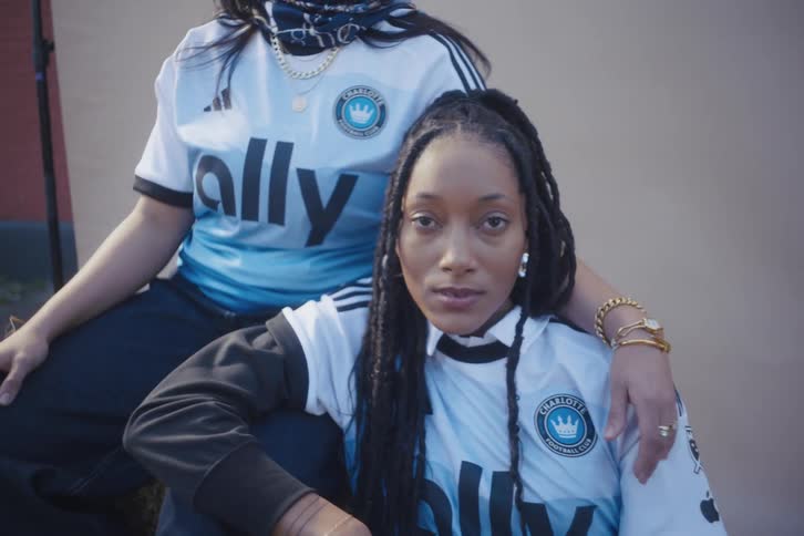 Two young models sitting outdoors posing in an adidas tshirt