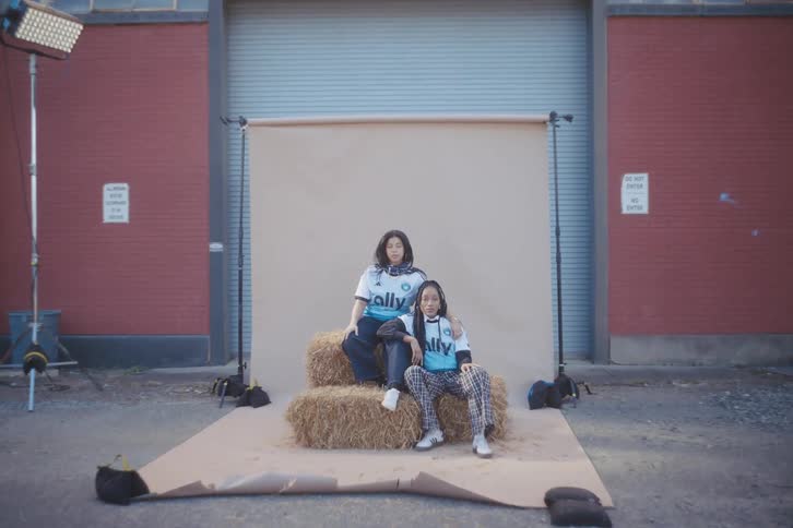 Two young models posing in adidas football shirts sitting on a haystack outdoors