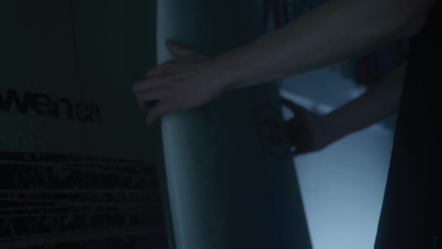 A person is taking a surfboard in a dark place