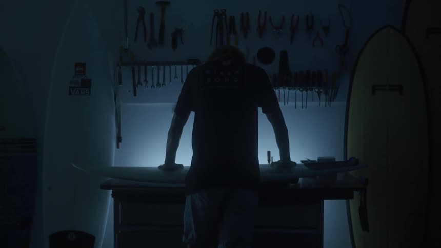 A man leans over the bench with his tools