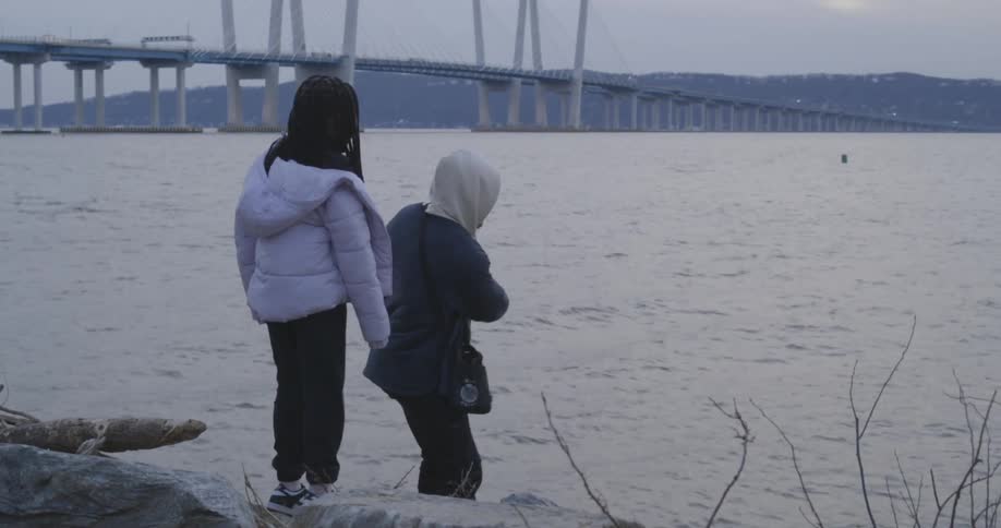 A father and daughter skip rocks on the shore