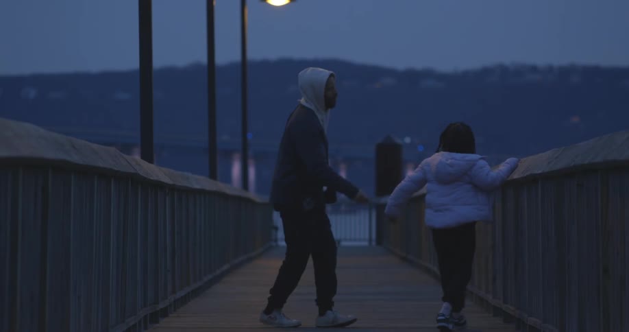 A boy and a little girl who are dancing and happy on a wooden walkway