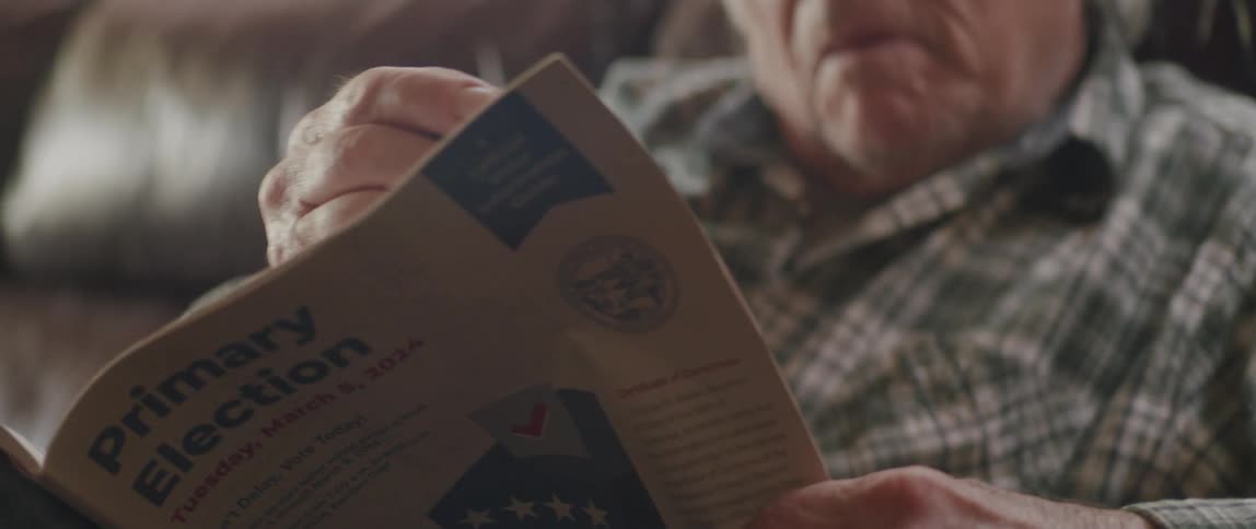 Portrait of an elderly man sitting in the living room concentrated reading a newspaper