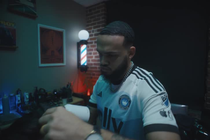 A man working in a barber shop combs and dries a clients hair
