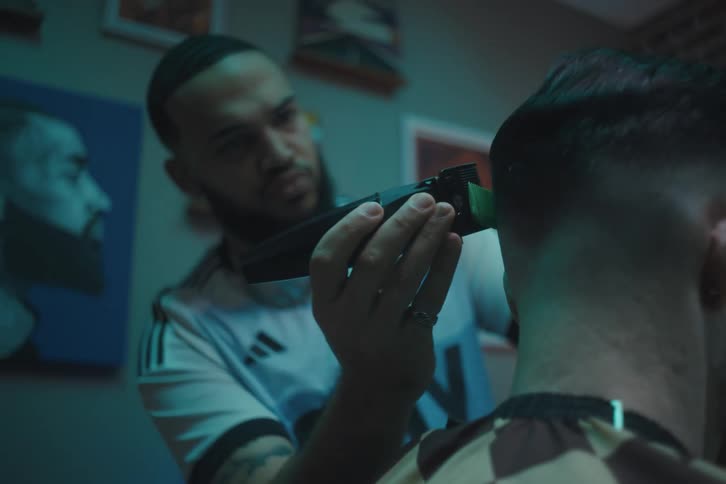 Barber using a small machine and a comb to cut a mans hair