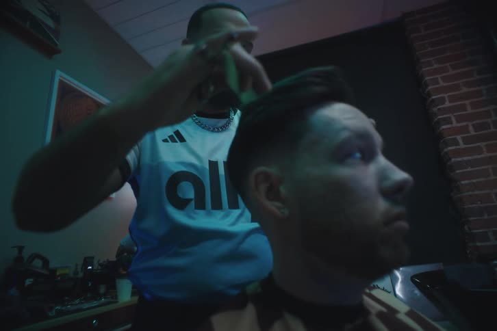 A barbershop with a man sitting while the barber is combing his hair