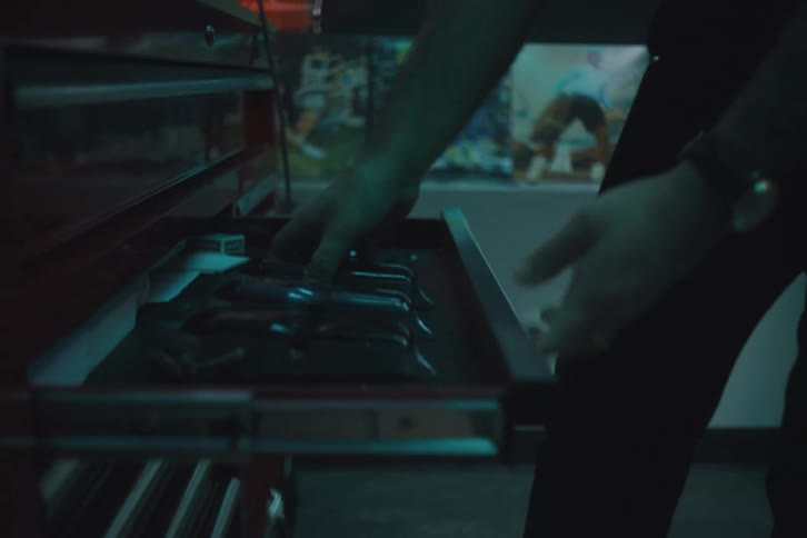 A man opens a red metal tool drawer and removes a tool