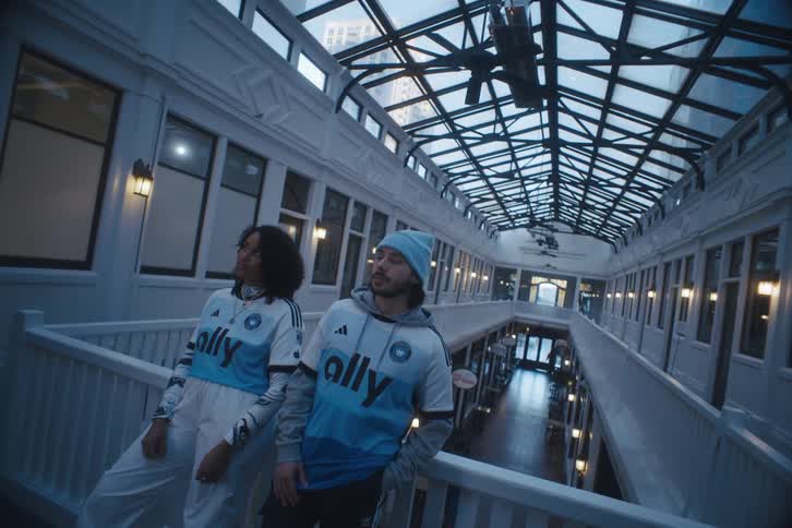 Man and woman lean against rail in building with glass ceiling