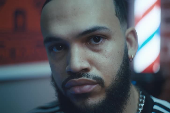 A young man with a beard and earring looking straight ahead
