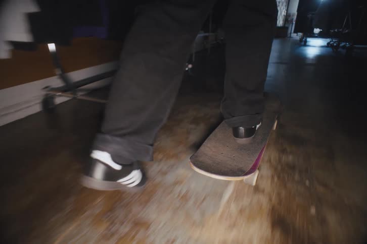 Legs of a person indoors riding a skateboard