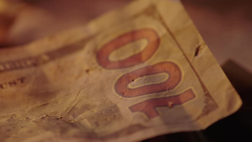 A flame lights up near a hundred dollar bill