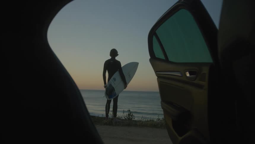 A surfer watches the sunrise