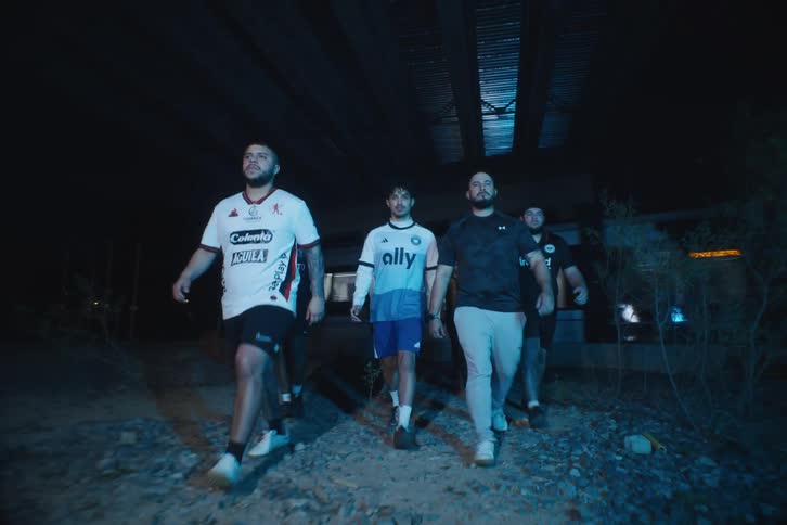 Group of male models walking below an overpass and next to a train in sportswear
