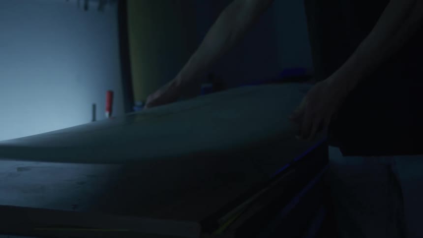 A man places the surfboard on the bench