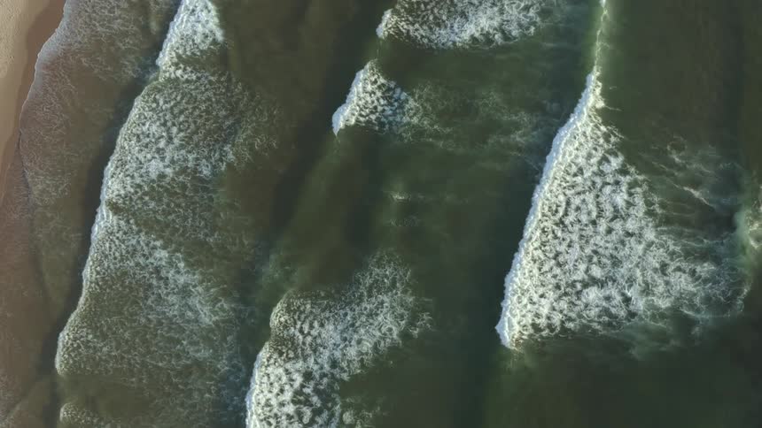 Aerial view of waves gently crashing on a beach