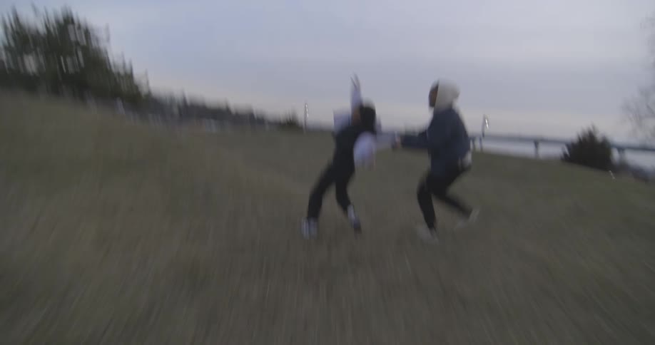 A father chases his daughter in a park on a winter day