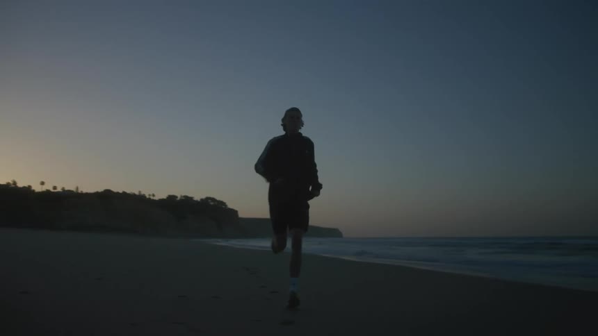 Man running on the beach sand next to the sea on a morning