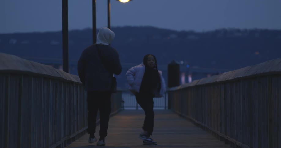 Father and daughter dancing over a bridge at night