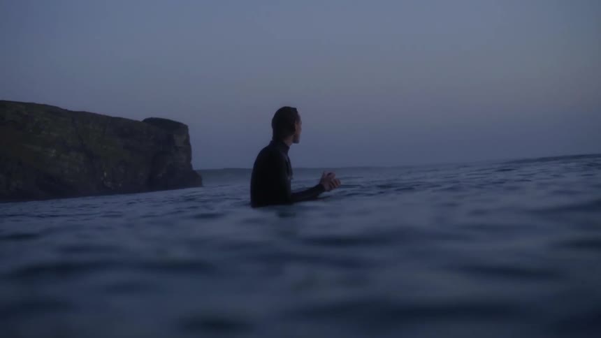 Surfer sitting on surfboard in the ocean waiting for a wave