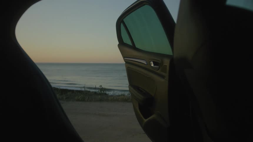 Car with the rear door open sits parked on highway at the shore