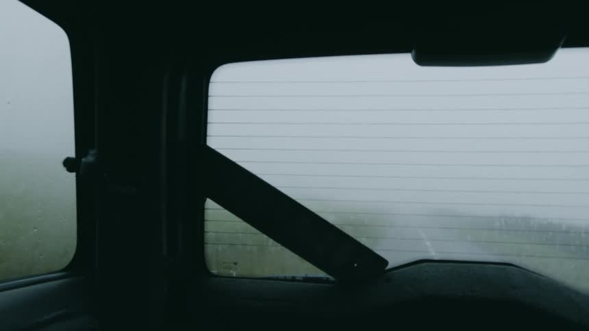 Rear windshield of a foggy vehicle traveling on asphalt in a foggy natural environment