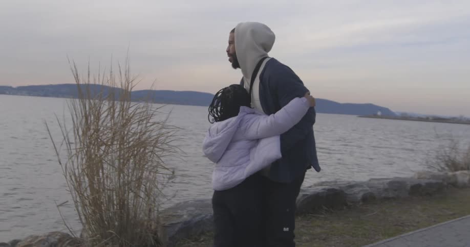 Daughter hugging her father while they are in a seaside square one morning