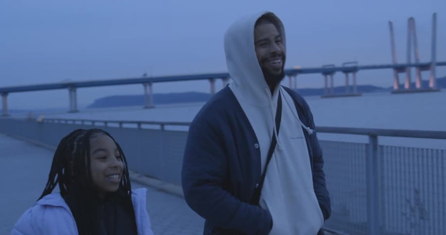 A father and daughter walk past the water