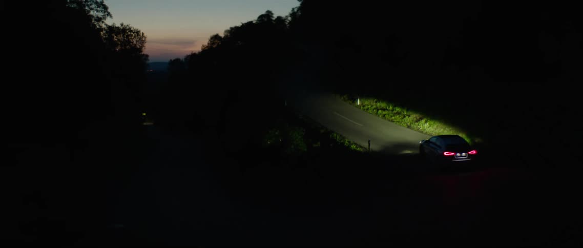 A car with headlights on driving on a road at night