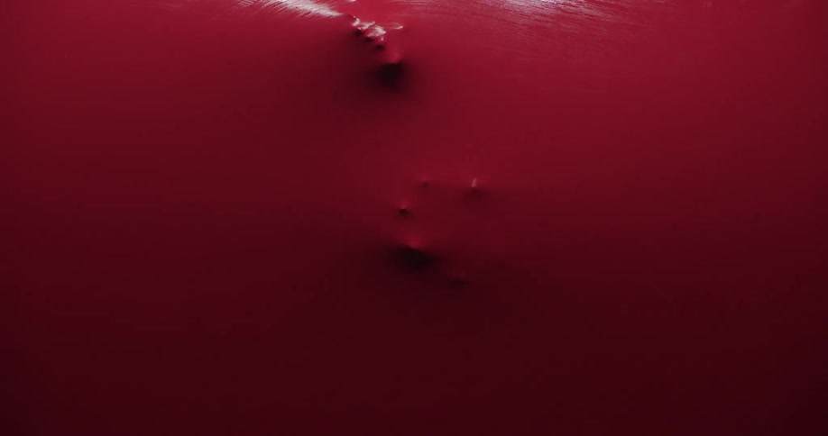 A person presses their fingertips against a red stretchable rubber sheet