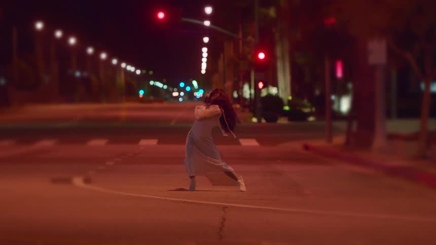 Woman dancing in the middle of an empty street in the city