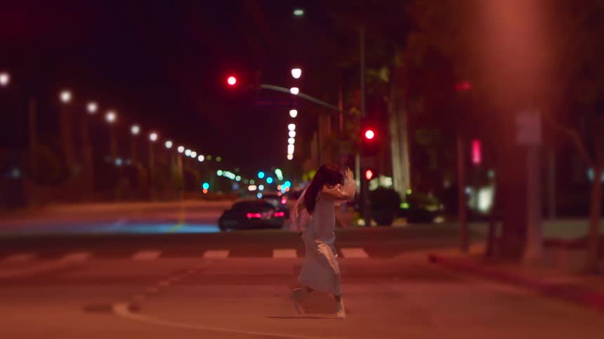 A woman dances in a city street at night