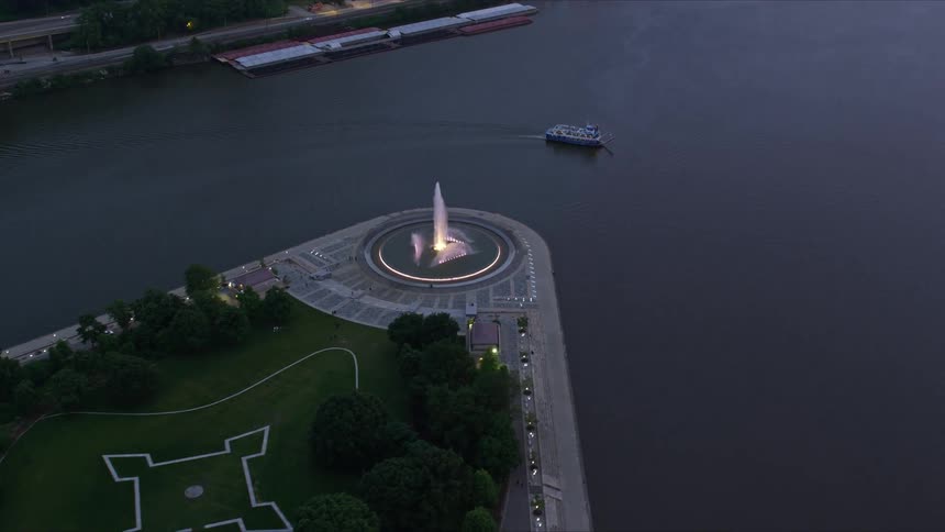 Aerial panorama of a square with a fountain on the edge of a sea canal with a boat passing by one morning