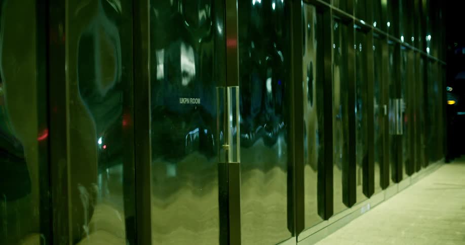Medium close shot of car reflections distorted in a glass office building