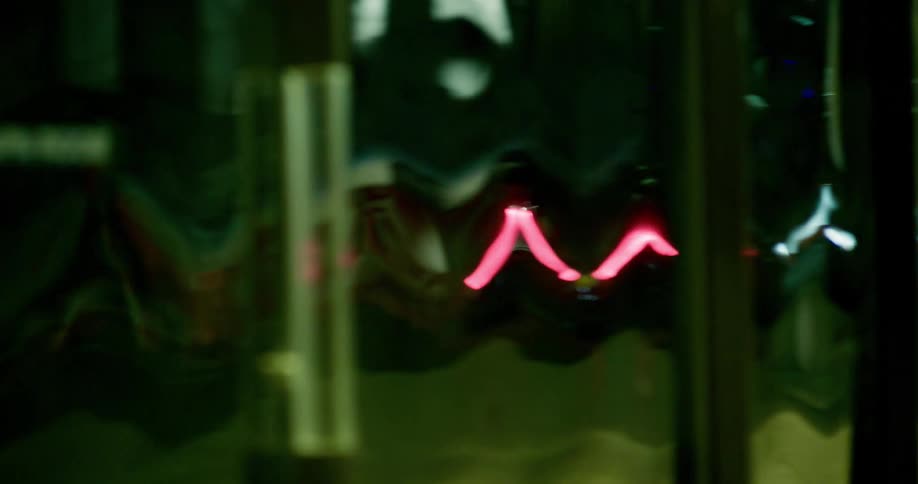 Reflection in a glass building  of a car's red  tail lights passing by