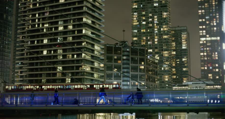 A train passes behind people walking on a footbridge over water