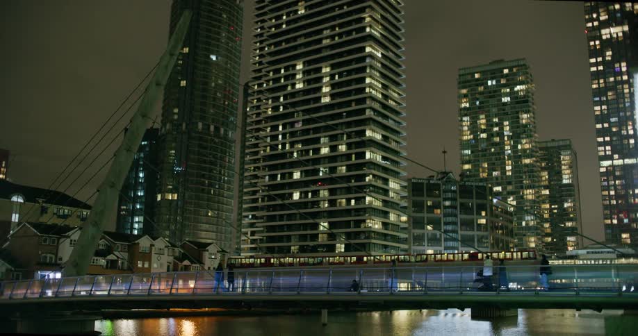 Panorama of a bridge over a river with pedestrian traffic and a view of a metropolis with buildings at night