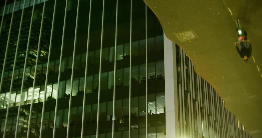Reflection on the roof of a building in a metropolis at night of a man pedaling his bicycle